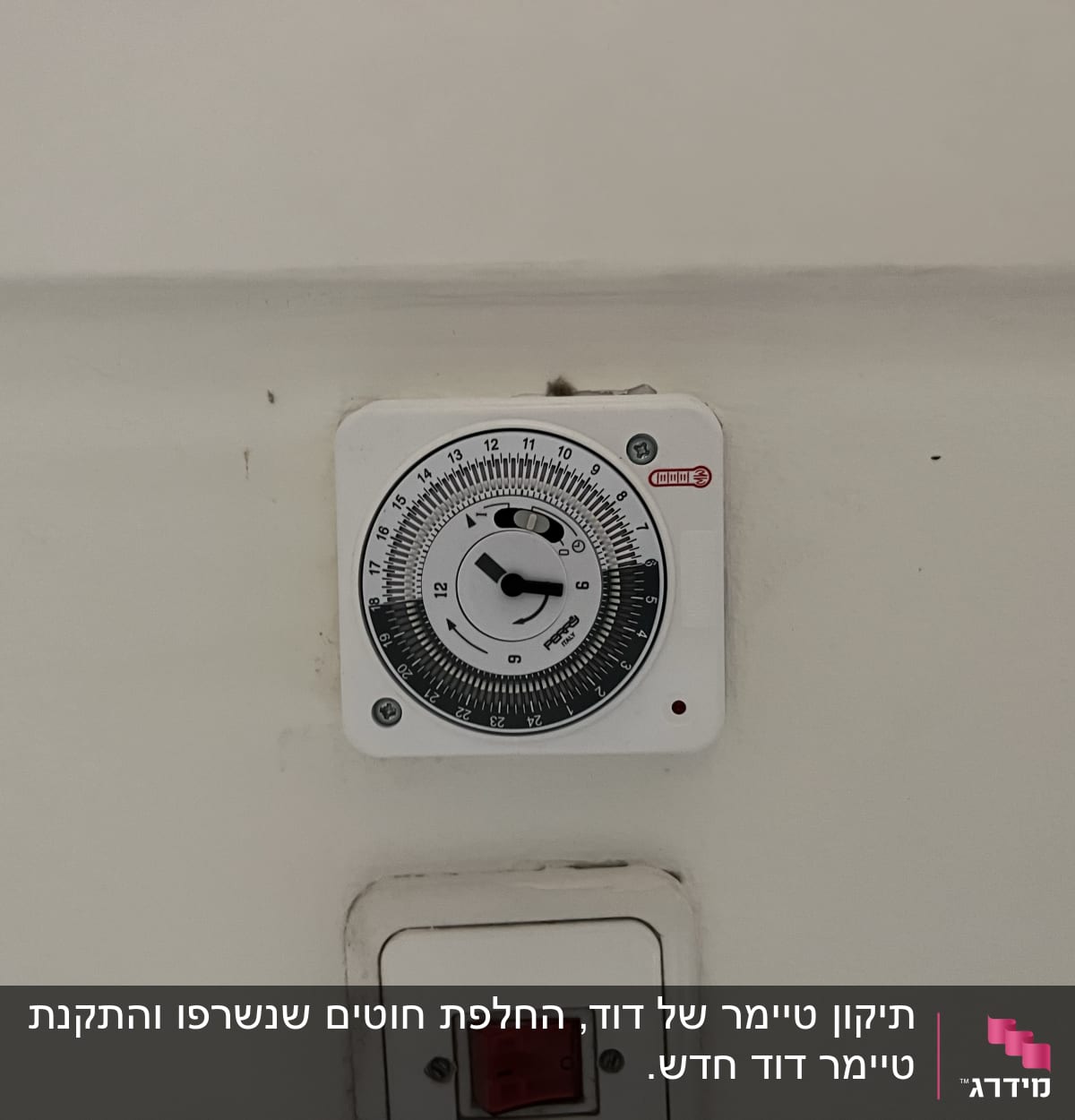 טיימר חשמלי מותקן על קיר עם מתג אדום